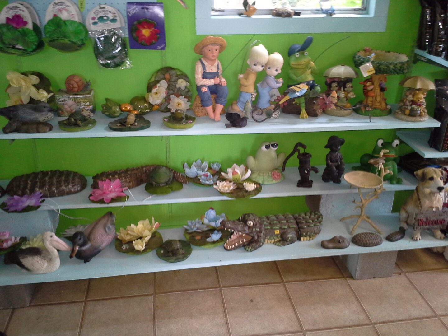 A green wall with several shelves of figurines.